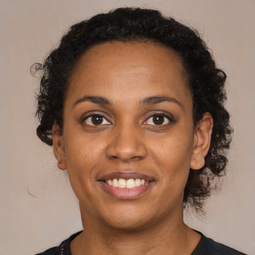 Joyful black young-adult female with long  brown hair and brown eyes