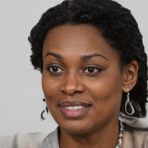 Joyful black young-adult female with long  black hair and brown eyes
