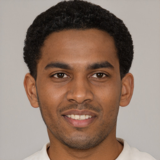 Joyful black young-adult male with short  black hair and brown eyes