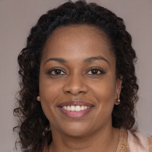Joyful black young-adult female with long  brown hair and brown eyes
