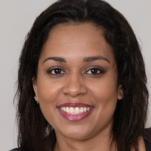 Joyful black young-adult female with long  brown hair and brown eyes