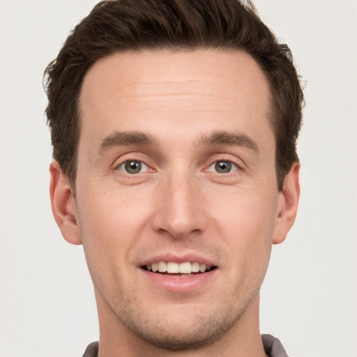 Joyful white young-adult male with short  brown hair and grey eyes