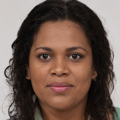 Joyful black young-adult female with long  brown hair and brown eyes