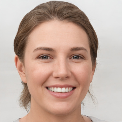 Joyful white young-adult female with medium  brown hair and grey eyes