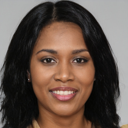 Joyful black young-adult female with long  black hair and brown eyes