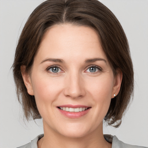 Joyful white young-adult female with medium  brown hair and grey eyes