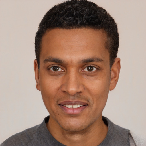 Joyful black young-adult male with short  black hair and brown eyes