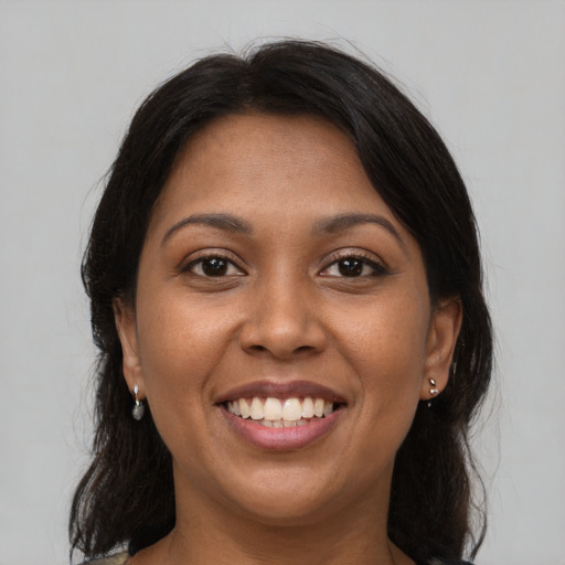 Joyful black young-adult female with long  brown hair and brown eyes