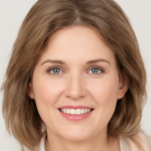 Joyful white young-adult female with medium  brown hair and green eyes