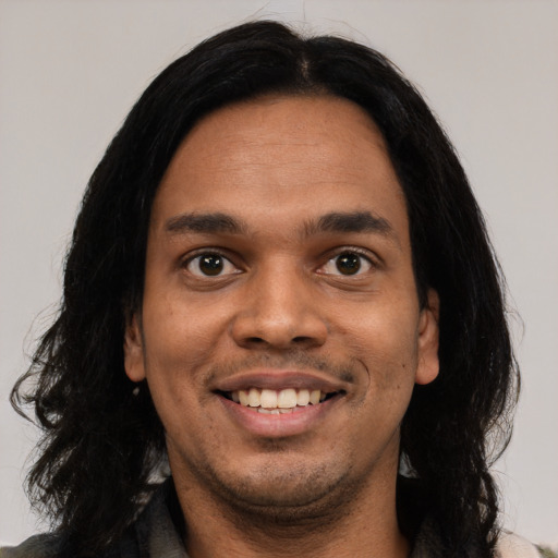 Joyful latino young-adult male with long  black hair and brown eyes