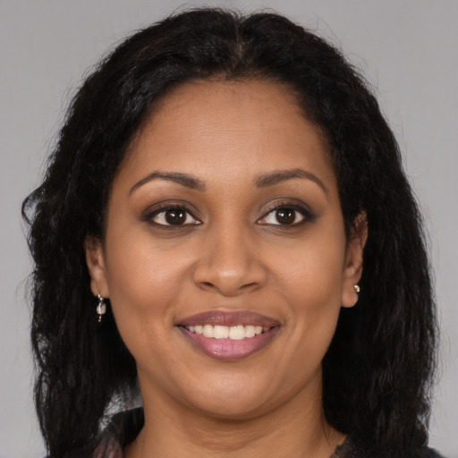 Joyful black young-adult female with long  brown hair and brown eyes