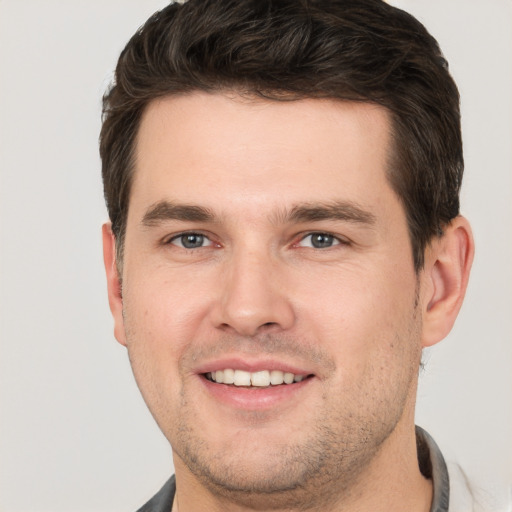 Joyful white young-adult male with short  brown hair and grey eyes