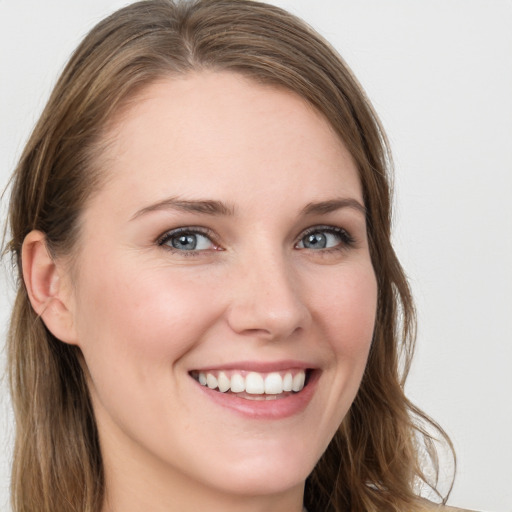 Joyful white young-adult female with long  brown hair and blue eyes