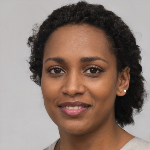 Joyful black young-adult female with long  black hair and brown eyes