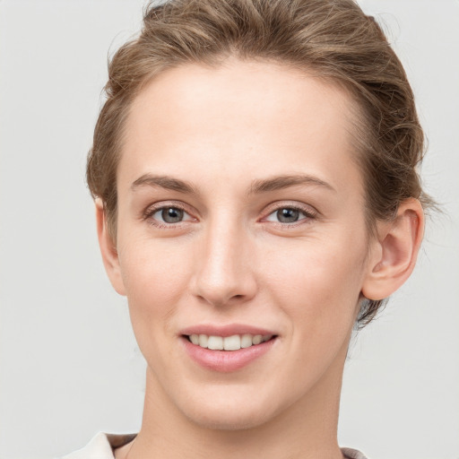 Joyful white young-adult female with short  brown hair and grey eyes