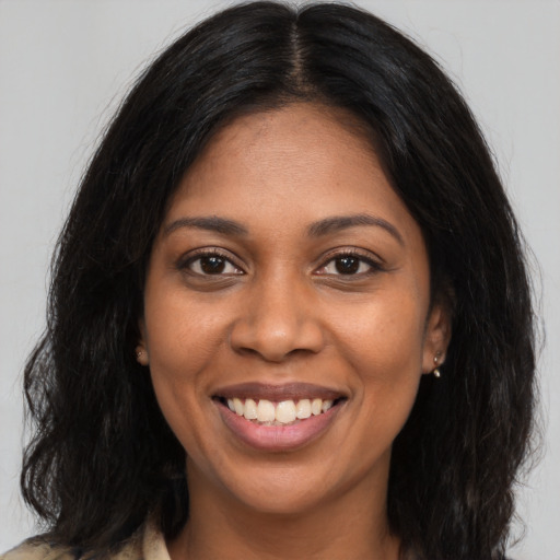 Joyful black young-adult female with long  brown hair and brown eyes