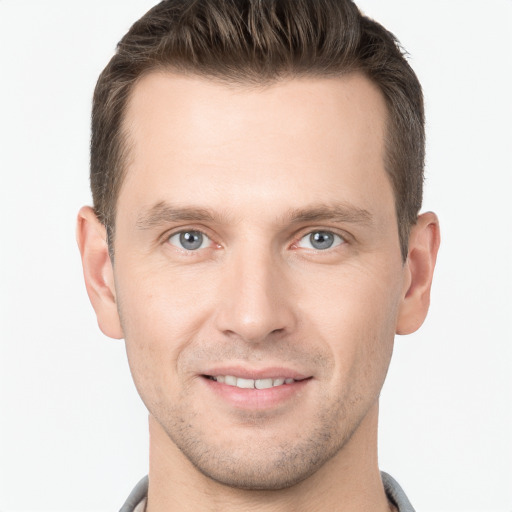 Joyful white young-adult male with short  brown hair and grey eyes