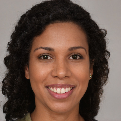 Joyful black young-adult female with long  brown hair and brown eyes