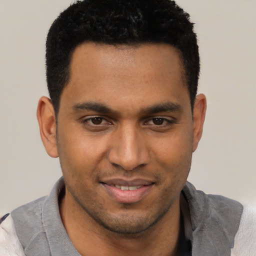 Joyful black young-adult male with short  black hair and brown eyes