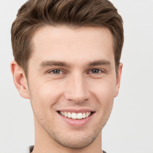 Joyful white young-adult male with short  brown hair and grey eyes