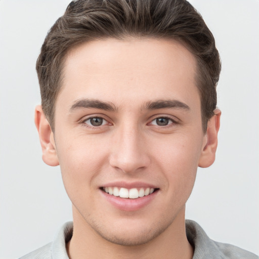 Joyful white young-adult male with short  brown hair and grey eyes