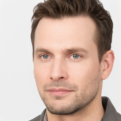 Joyful white young-adult male with short  brown hair and grey eyes