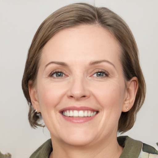 Joyful white adult female with medium  brown hair and grey eyes