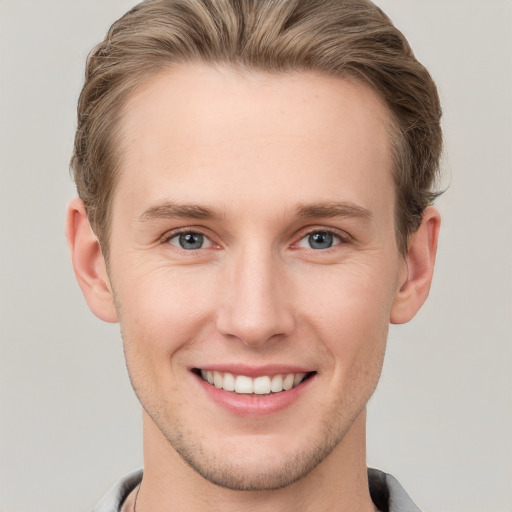 Joyful white young-adult male with short  brown hair and grey eyes