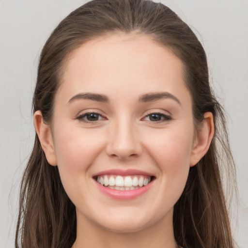 Joyful white young-adult female with long  brown hair and brown eyes