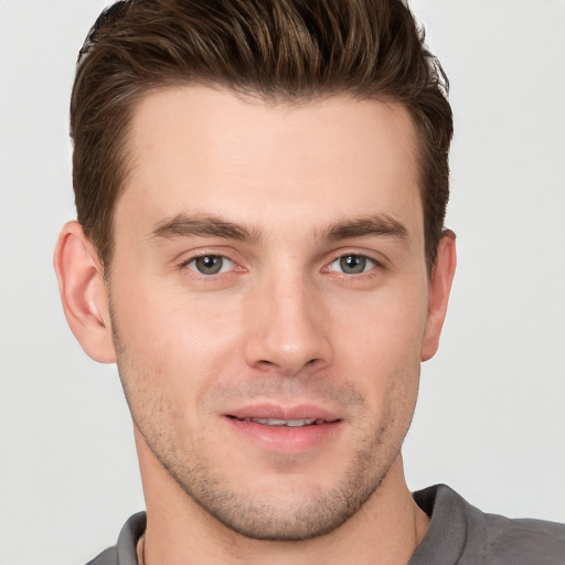 Joyful white young-adult male with short  brown hair and grey eyes