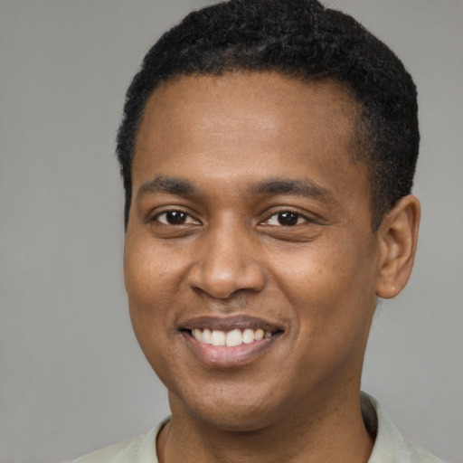 Joyful black young-adult male with short  brown hair and brown eyes