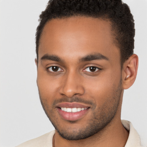 Joyful black young-adult male with short  brown hair and brown eyes