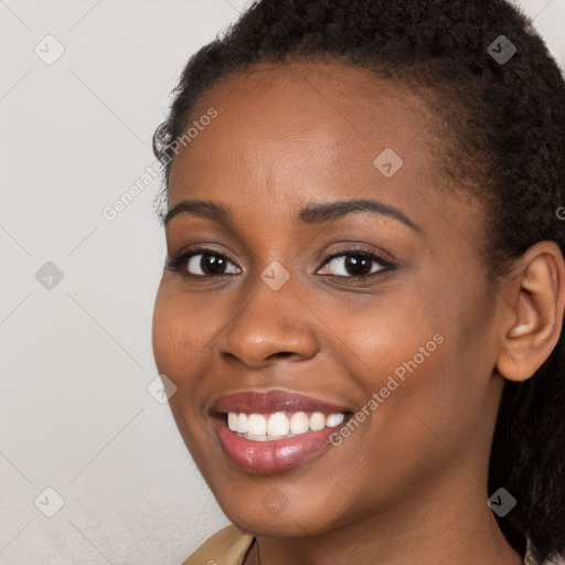 Joyful black young-adult female with long  brown hair and brown eyes