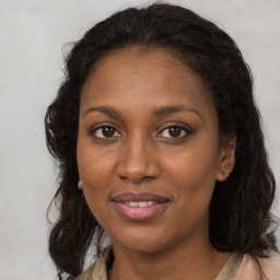 Joyful black young-adult female with long  brown hair and brown eyes