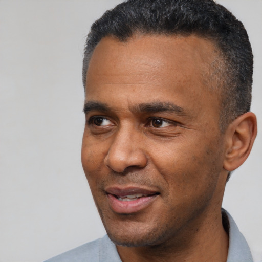 Joyful black adult male with short  black hair and brown eyes
