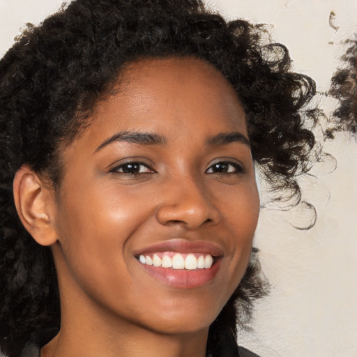 Joyful black young-adult female with long  brown hair and brown eyes