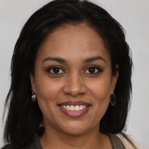 Joyful black young-adult female with long  brown hair and brown eyes
