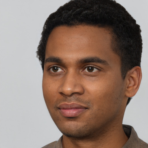 Joyful black young-adult male with short  black hair and brown eyes