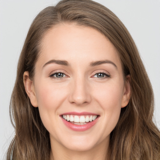 Joyful white young-adult female with long  brown hair and grey eyes