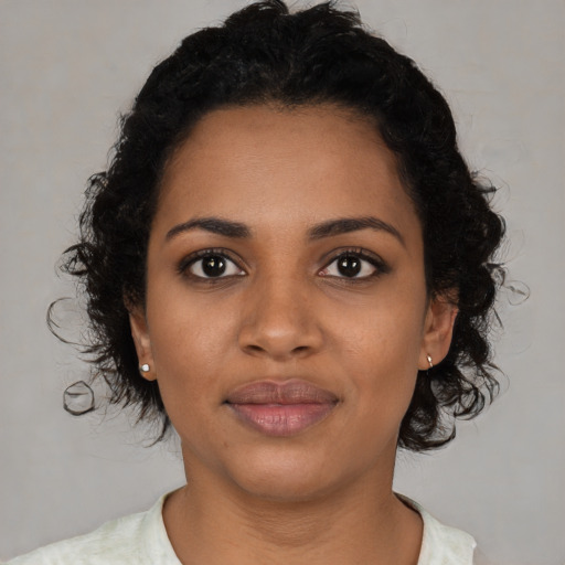 Joyful black young-adult female with short  black hair and brown eyes