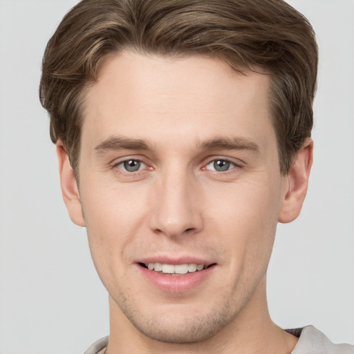 Joyful white young-adult male with short  brown hair and grey eyes