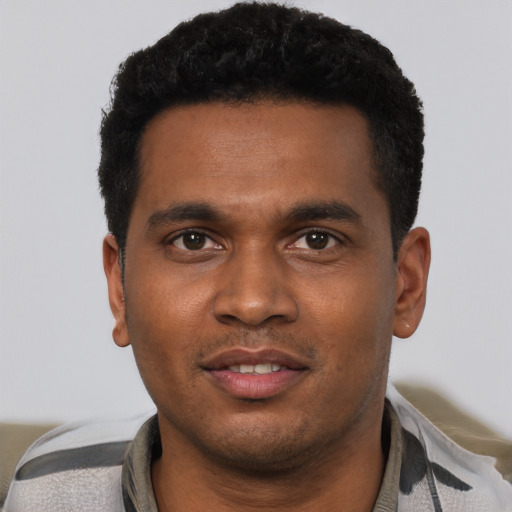 Joyful black young-adult male with short  black hair and brown eyes