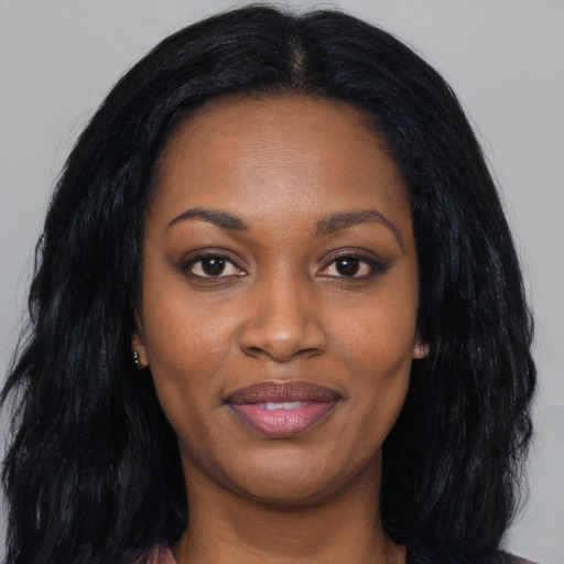 Joyful black young-adult female with long  black hair and brown eyes