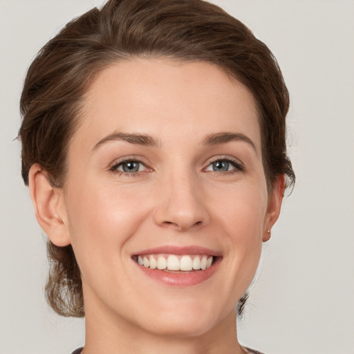 Joyful white young-adult female with medium  brown hair and grey eyes