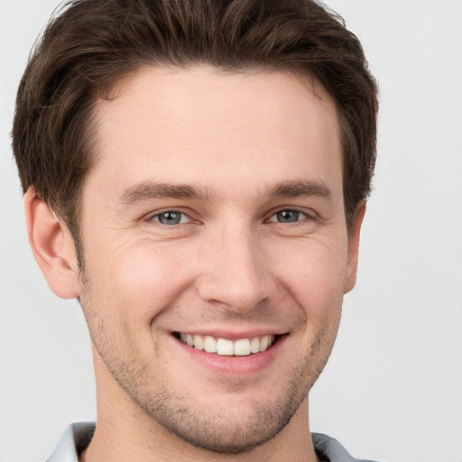 Joyful white young-adult male with short  brown hair and grey eyes