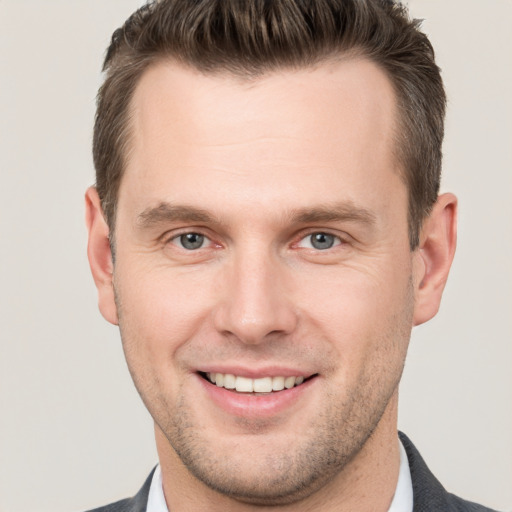 Joyful white young-adult male with short  brown hair and grey eyes