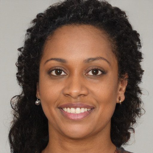 Joyful black young-adult female with long  brown hair and brown eyes