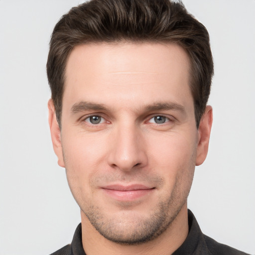 Joyful white young-adult male with short  brown hair and grey eyes