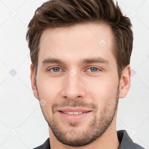 Joyful white young-adult male with short  brown hair and grey eyes