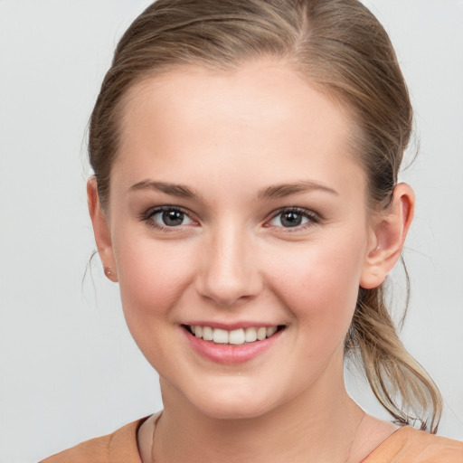 Joyful white young-adult female with medium  brown hair and grey eyes